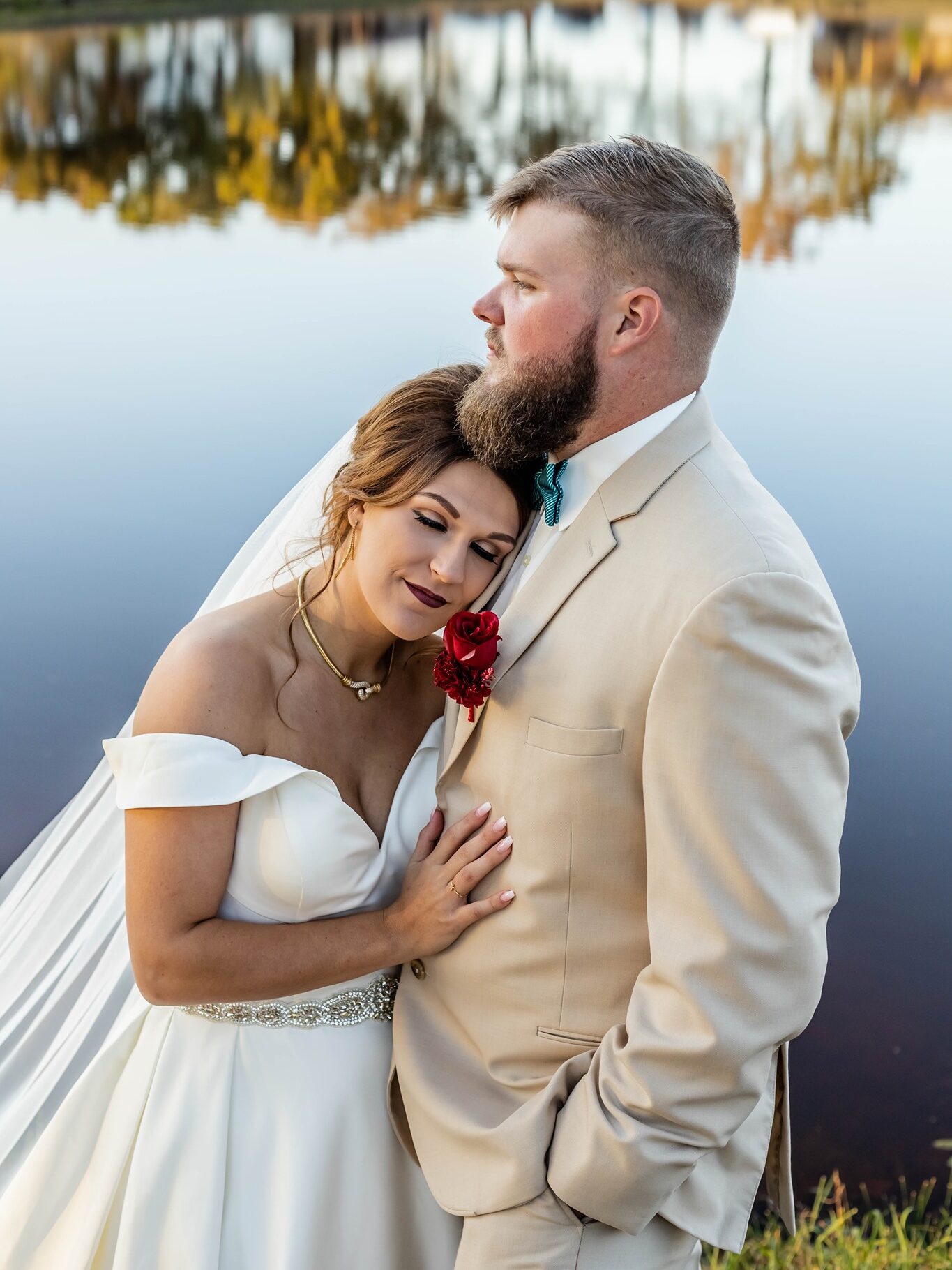 bride and groom embracing next to pond