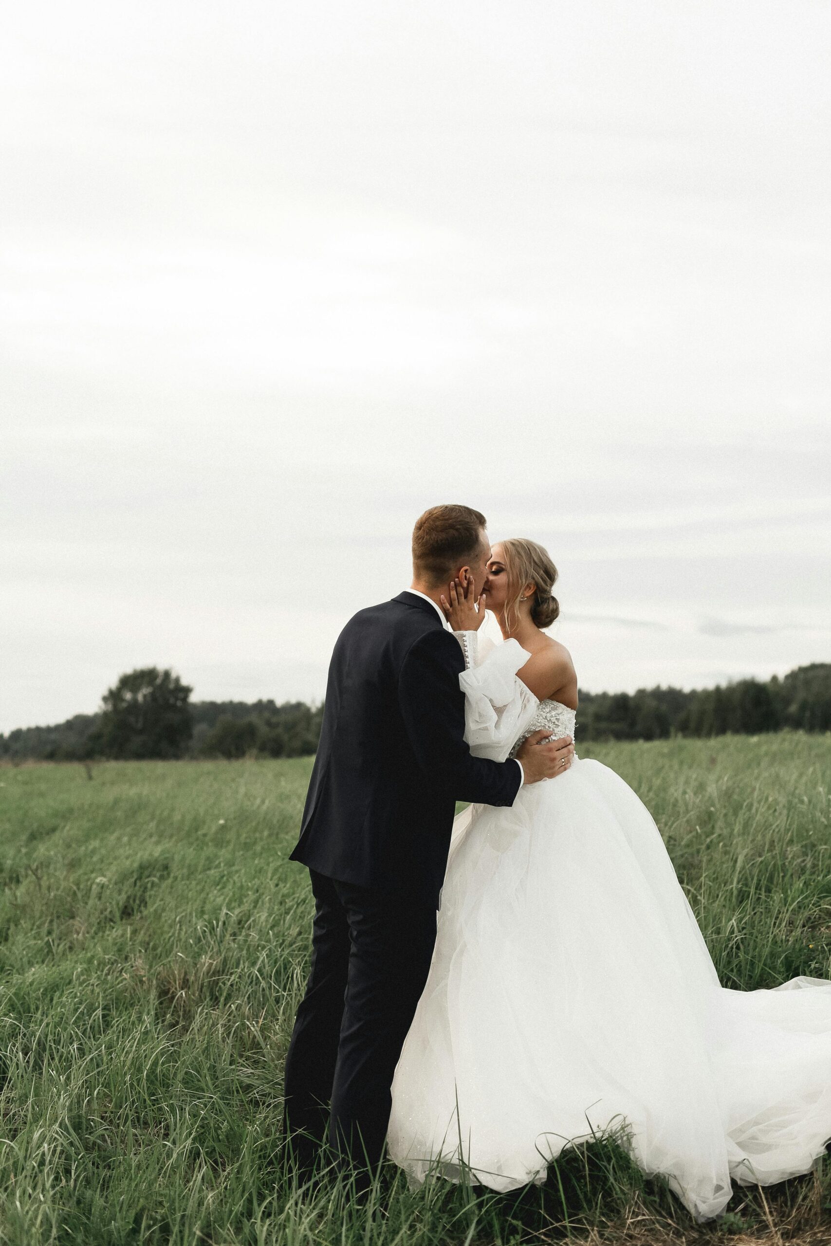 bride and groom kissing in green field